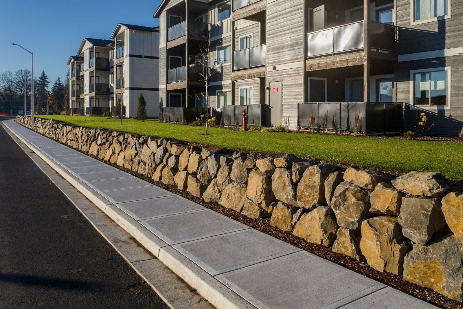 Basalt boulder retaining wall and lawn terrace, commercial hardscape construction